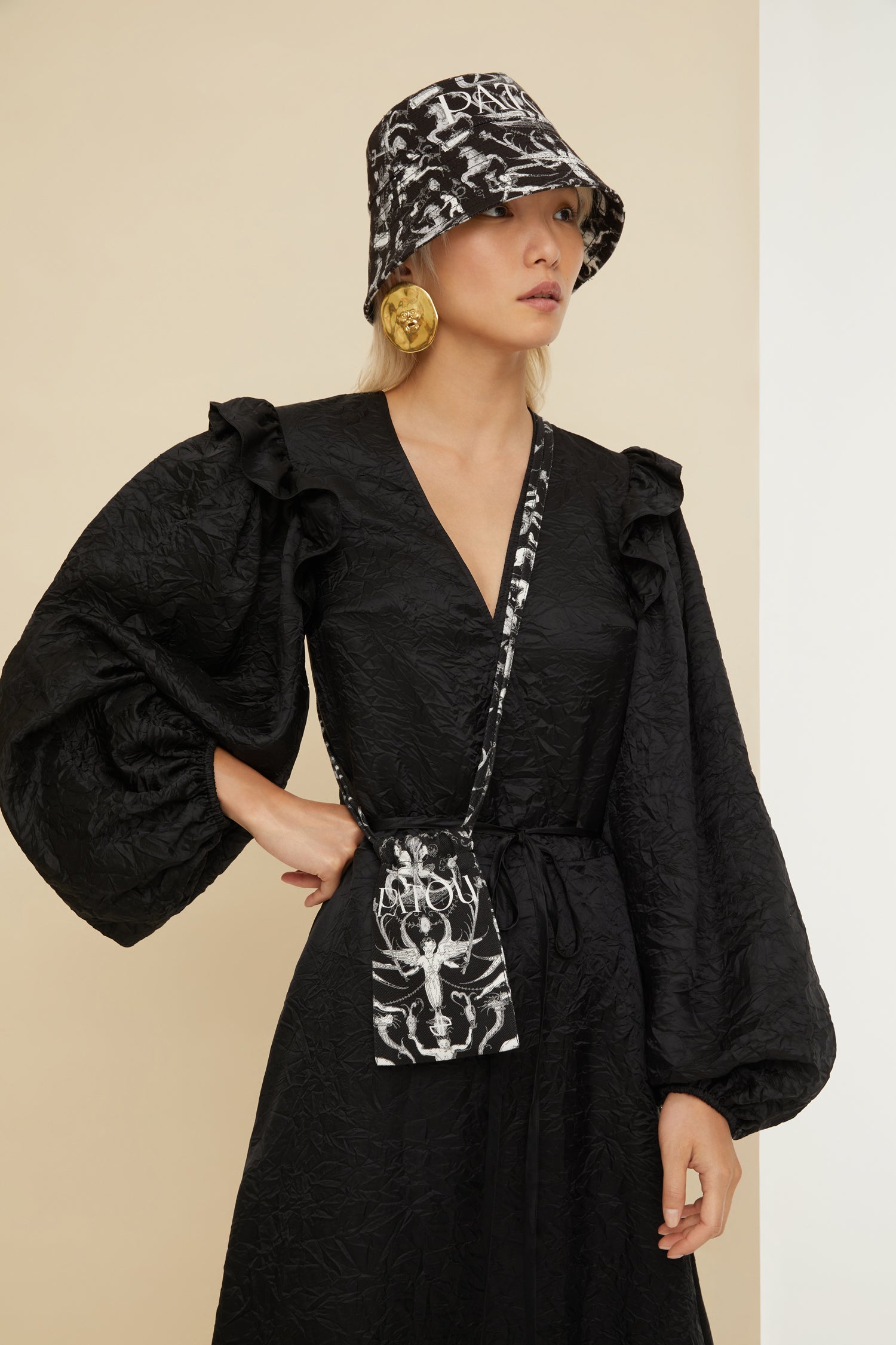 Patou - Robe longue décolletée en satin éco responsable - Black - Le satin froissé apporte fraîcheur et légèreté aux tenues de soirée. Robe en satin éco-responsable noir. Effet froissé. Longueur maxi. Buste croisé à col en V. Volants sur les épaules. Manches ballon à poignets élastiqués. Fine ceinture en tissu à la taille
