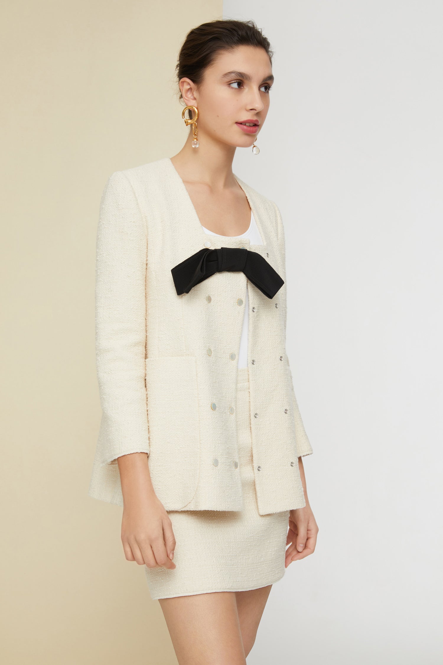 Patou - Jacke mit Schleife aus Baumwoll-Tweed - Sand - Die Tweed-Jacke mit der Patou-Note. Sandweiße Jacke aus Baumwoll-Tweed. Doppelreihig. Quadratischer Halsausschnitt mit abnehmbarer schwarzer Schleife vorne. Leicht ausgestellte Ärmel mit Knöpfen an den Bundabschlüssen. Patou-Aufnäher im Tailor-Stil am linken Ärmel. Zwei große aufgesetzte Taschen. Hinten einfach geschlitzt. Gefüttert.