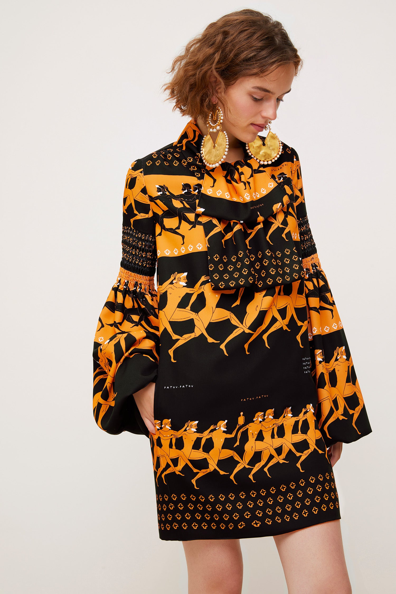 Patou - Vestito corto stampato con collo lavallière - Sport Education Print - Pagoda e lavallière: il fascino dei dettagli couture.Vestito corto in poliestere con collo lavallière. Disegni ispirati alla Grecia antica sul tema dell'educazione sportiva con riferimenti agli elementi iconici della storia Patou. Maniche a pagoda. Dettagli nido d'ape su spalle, maniche e collo. Tasche laterali nascoste. Chiusura con cerniera. Interamente foderato.