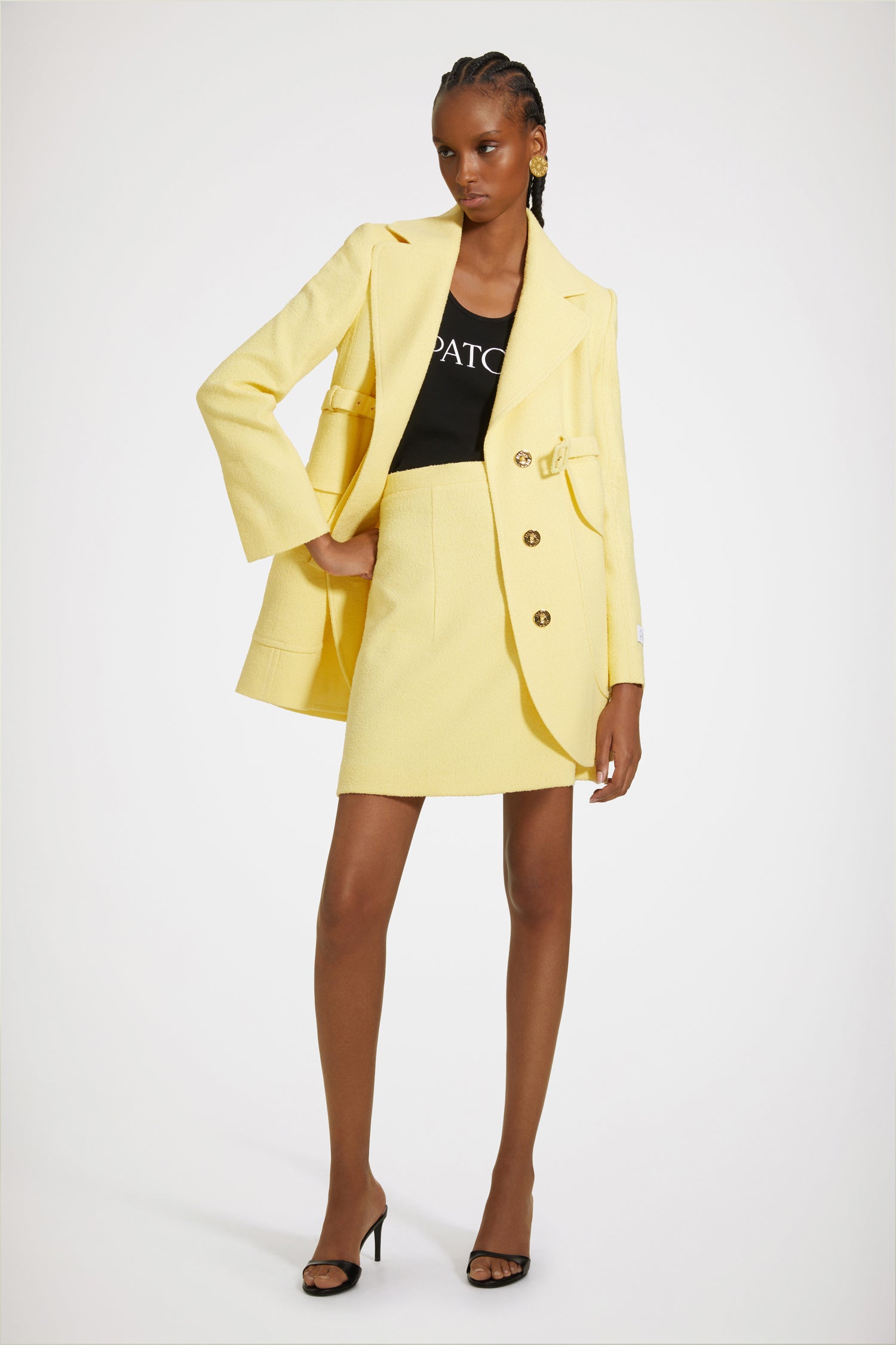 Patou - Longline belted jacket in cotton-blend tweed - Mimosa - Patou, a master tailor for the new generation. Mimosa yellow cotton-blend tweed jacket. Longline silhouette. Notch lapels. Concealed button fastening at the front with gold-tone Patou-engraved buttons. Signature curved seam at the back. Adjustable buckle belt that sits high at the waist. Maxi flap patch pockets at the front. Patou label on the left sleeve. Split cuffs. High back vent. Fully lined.Spring-Summer 2023 Show - Look #16