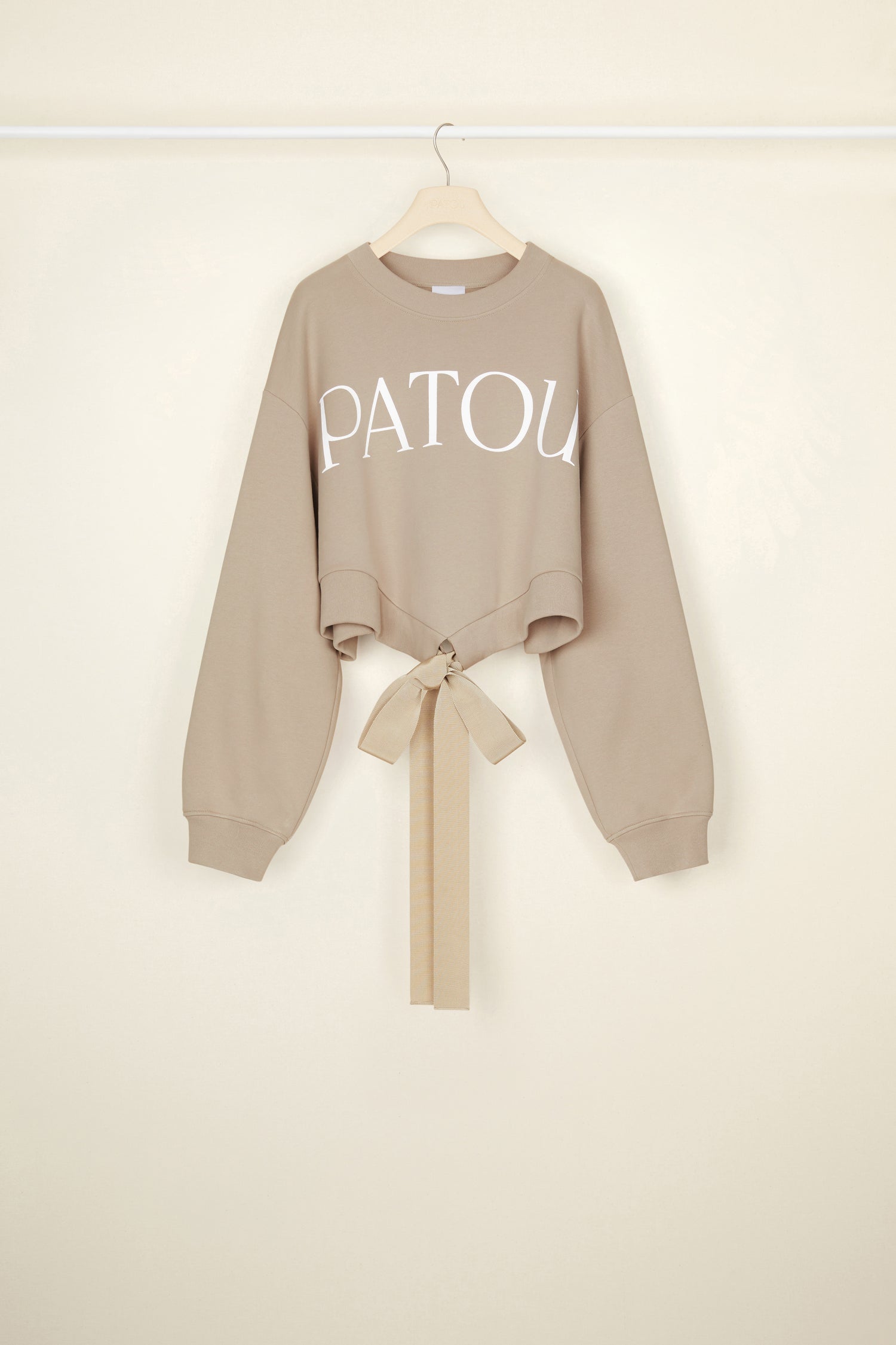 Patou - Cropped grosgrain sweatshirt in organic cotton - Parchment - Comfort with a side of couture: the sweatshirt by Patou.Parchment beige organic cotton sweatshirt. Loose cropped silhouette. Crewneck. Rib knit collar and cuffs. Oversized Patou lettering logo in white across the front. Drawstring waistband with long grosgrain ties.