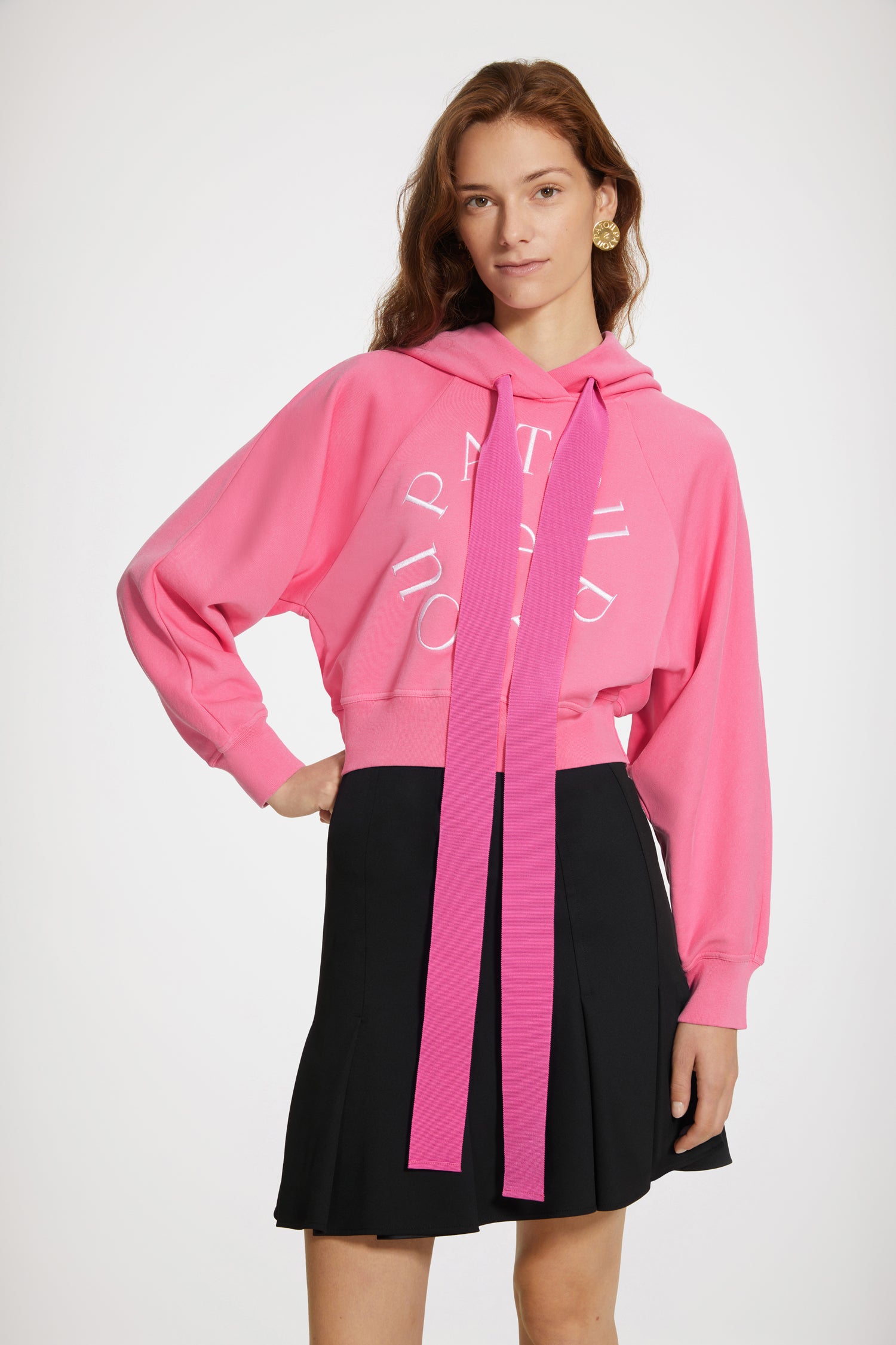 Patou - Medallion logo cropped hoodie in organic cotton - Begonia Pink - Five letters and a grosgrain bow, a Patou recipe for success. Begonia pink organic cotton sweatshirt. Cropped silhouette. Hooded collar with grosgrain drawstring. Patou medallion logo embroidered at the front. Raglan sleeves. Ribbed cuffs and waist.