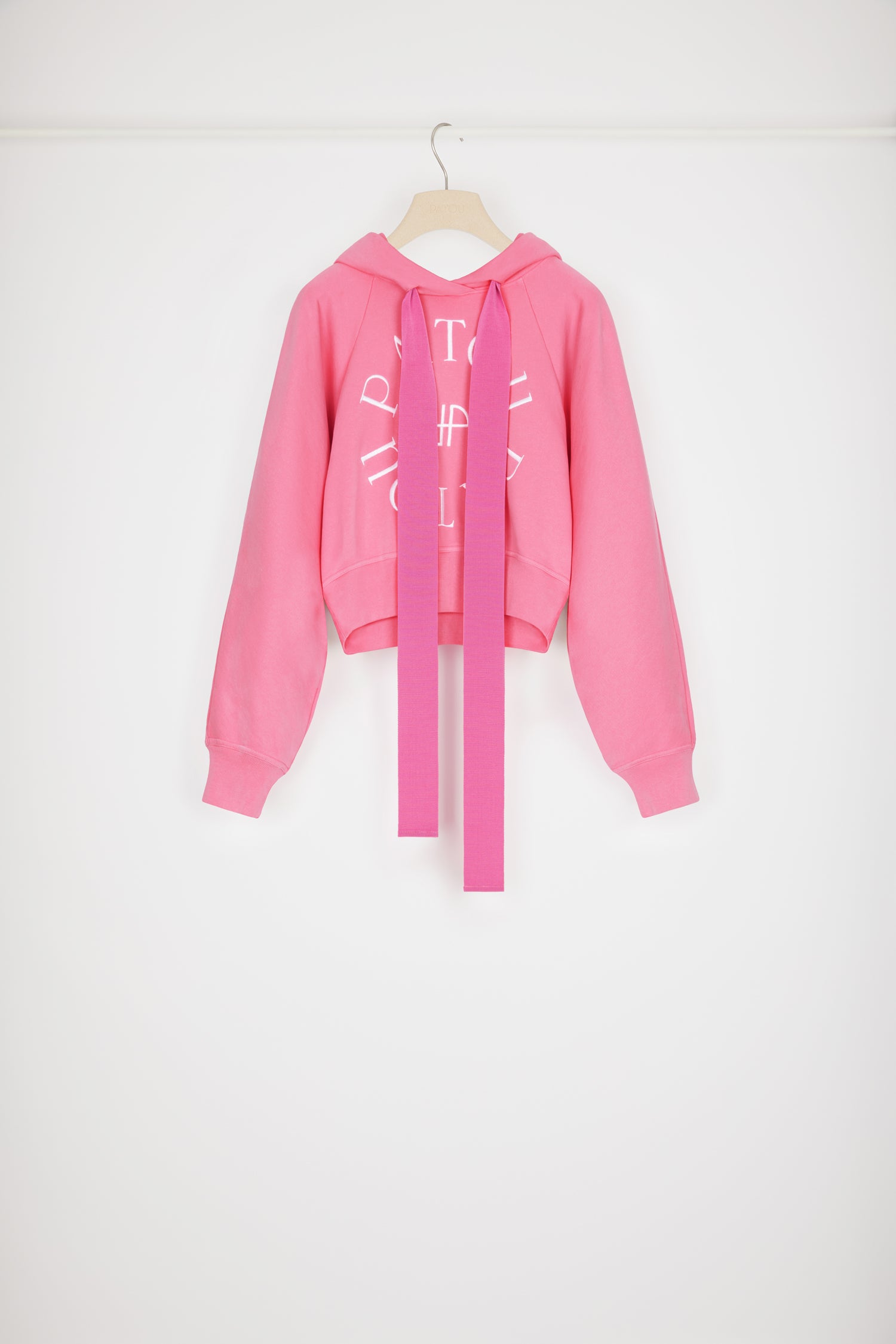 Patou - Medallion logo cropped hoodie in organic cotton - Begonia Pink - Five letters and a grosgrain bow, a Patou recipe for success. Begonia pink organic cotton sweatshirt. Cropped silhouette. Hooded collar with grosgrain drawstring. Patou medallion logo embroidered at the front. Raglan sleeves. Ribbed cuffs and waist.