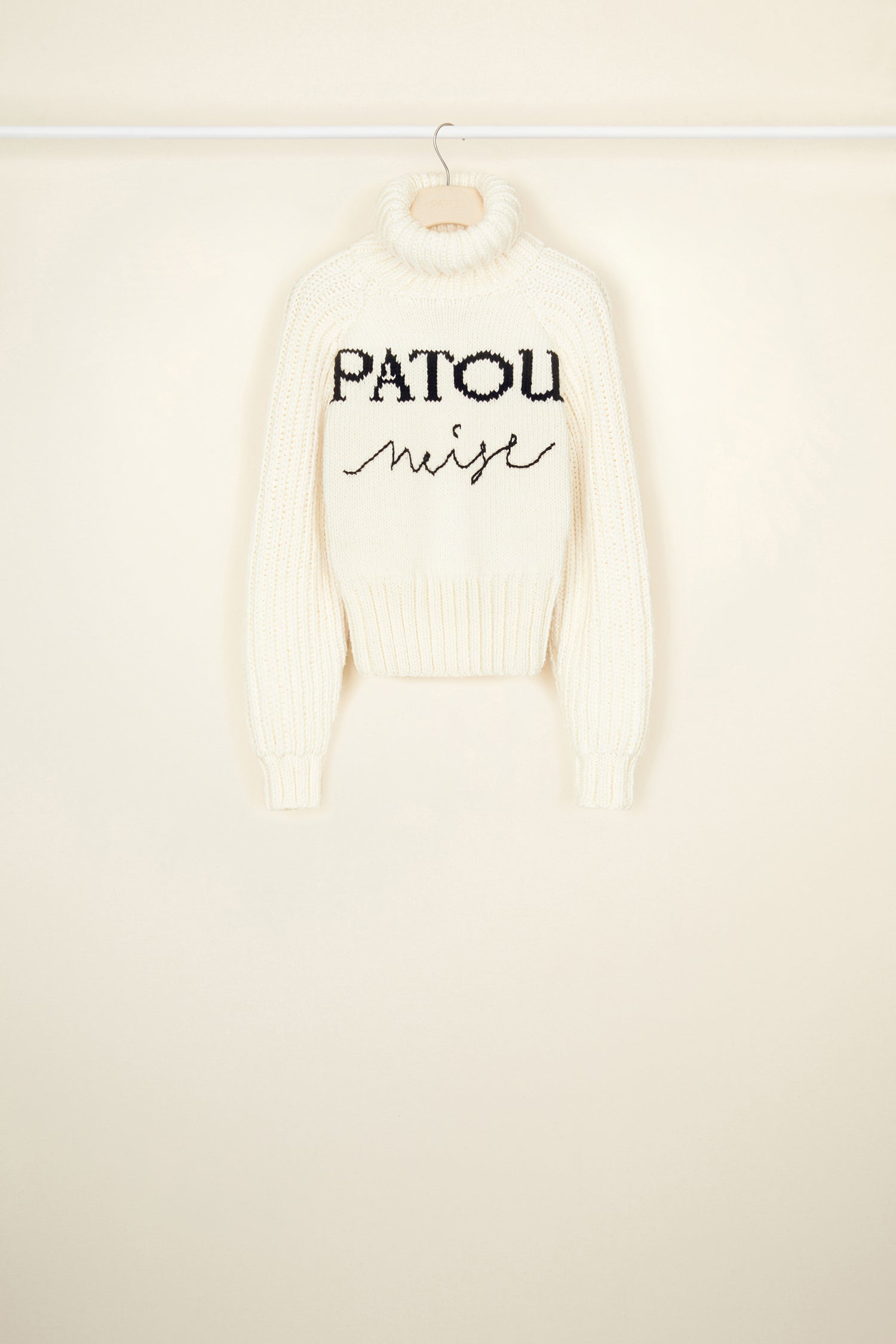 Patou - Patou Neige wool jumper - Ivory - Smile for the winter in the cosiest Patou jumper. Ivory Merino wool jumper. Part of the Patou Neige collection. Hand knitted garment featuring multiple stitch styles. Cropped, fitted silhouette. Turtleneck collar. High volume sleeves. Black Patou Neige signature and handwriting logo.