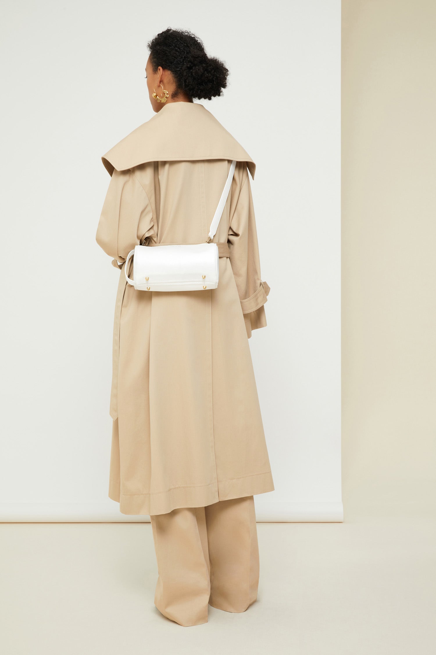 Patou - Charakteristischer Trenchcoat aus Bio-Baumwolle - Sand - Ein ausgestellter Trenchcoat mit französischem Flair. Charakteristischer Patou Trenchcoat aus sandbeiger Bio-Baumwoll-Gabardine. Doppelreihig mit leichter A-Linie. Übergroßer Kragen und Sturmklappe. Goldfarbene Knöpfe mit Patou Logo-Gravur. Abnehmbarer Taillengürtel. Bindebänder an den Manschetten mit schwarzem gestickten Patou Etikett. Zwei Seitentaschen. Vollständig gefüttert.