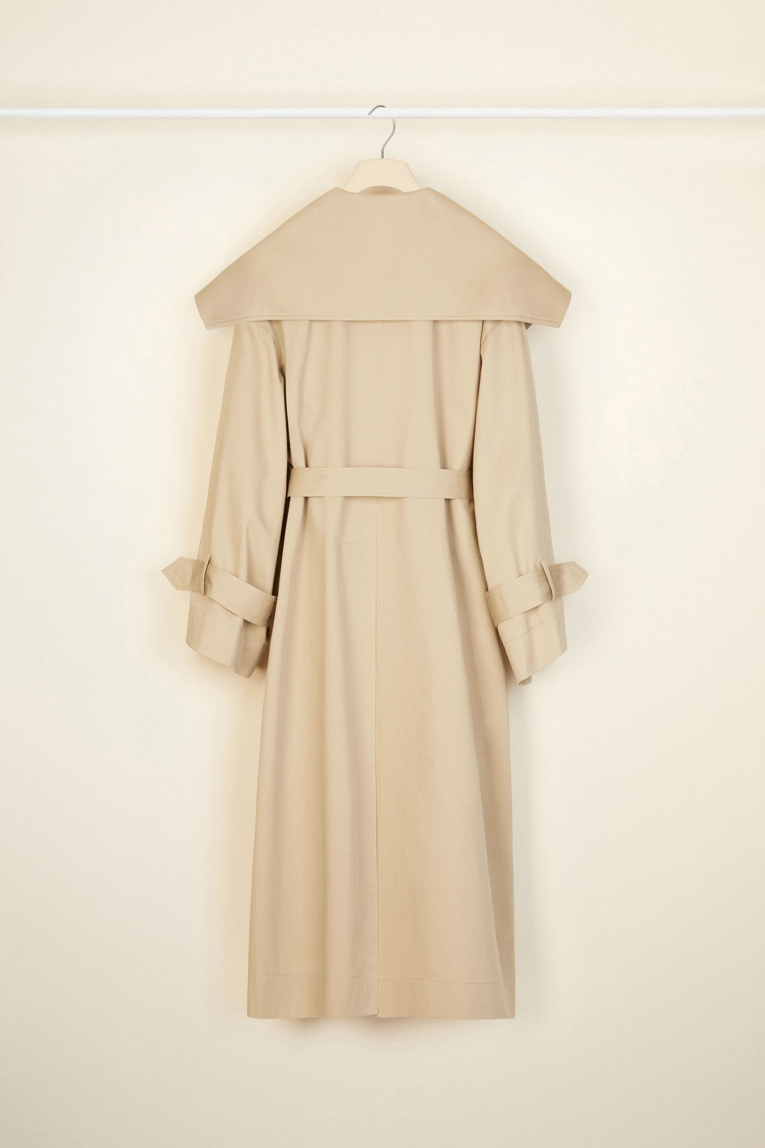 Patou - Charakteristischer Trenchcoat aus Bio-Baumwolle - Sand - Ein ausgestellter Trenchcoat mit französischem Flair. Charakteristischer Patou Trenchcoat aus sandbeiger Bio-Baumwoll-Gabardine. Doppelreihig mit leichter A-Linie. Übergroßer Kragen und Sturmklappe. Goldfarbene Knöpfe mit Patou Logo-Gravur. Abnehmbarer Taillengürtel. Bindebänder an den Manschetten mit schwarzem gestickten Patou Etikett. Zwei Seitentaschen. Vollständig gefüttert.