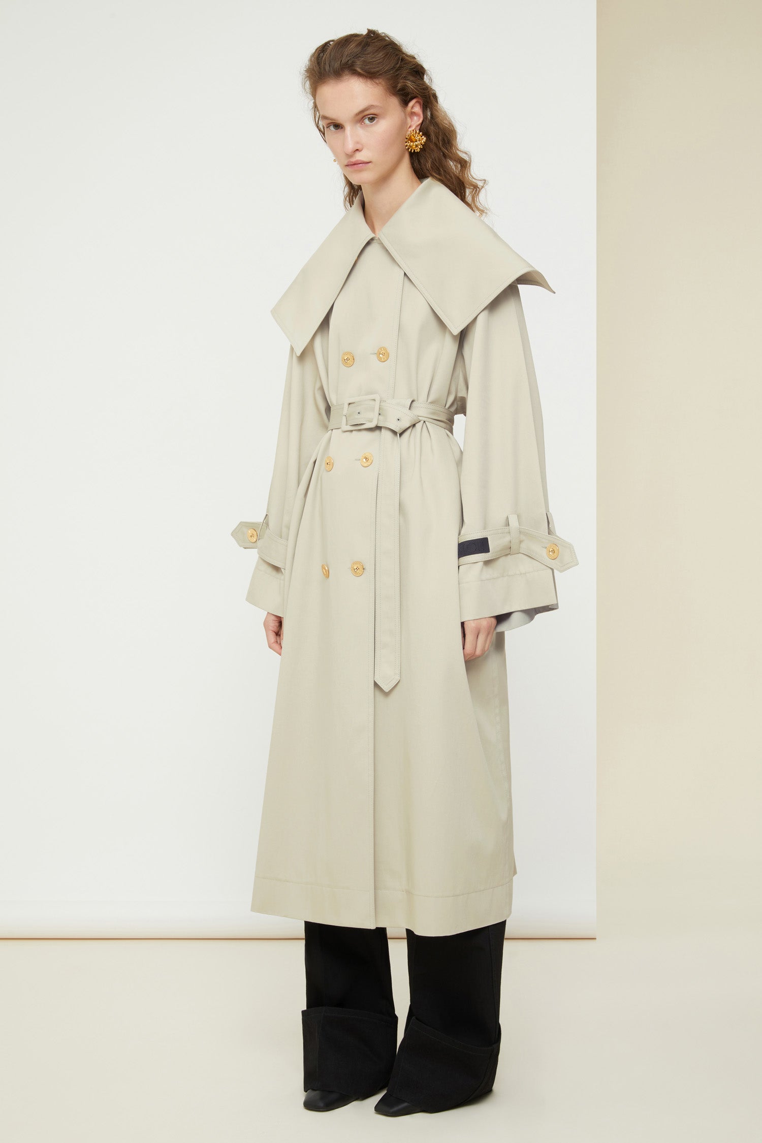 Patou - Signature trenchcoat in organic cotton - Silvery Moon - A flared trench with French flair.Signature Patou trenchcoat in Silvery Moon pale grey organic cotton gabardine. Double-breasted style with a slight A-line silhouette. Oversized collar and storm flap. Gold-coloured buttons with engraved Patou logo. Removable belt at the waist. Ties at the cuffs with black embroidered Patou label. Two pockets at the sides. Fully lined. Oversize fit.