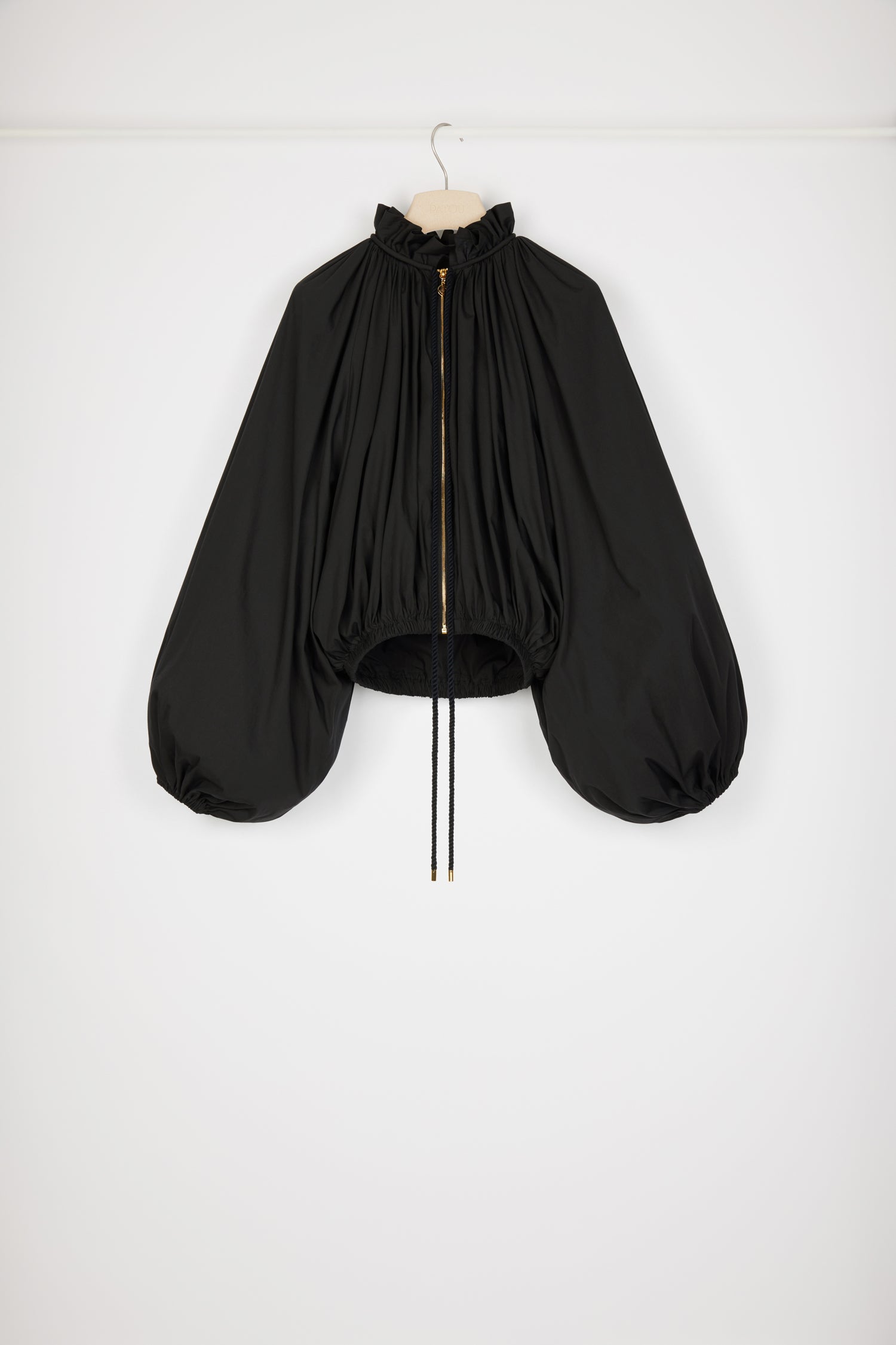 Patou - Bomber en coton bio mélangé - Black - Un bomber bouffant et bluffant. Bomber en coton bio mélangé noir. Modèle léger pouvant aussi être porté en tant que blouse. Coupe courte et volumineuse. Plissé à l'avant et au dos. Col haut à volant ; coulisse en corde avec embouts dorés. Zip doré avec tirette JP signature. Manches ballon à poignets élastiqués. Taille élastiquée.Look #06 du Show Printemps-Eté 2023