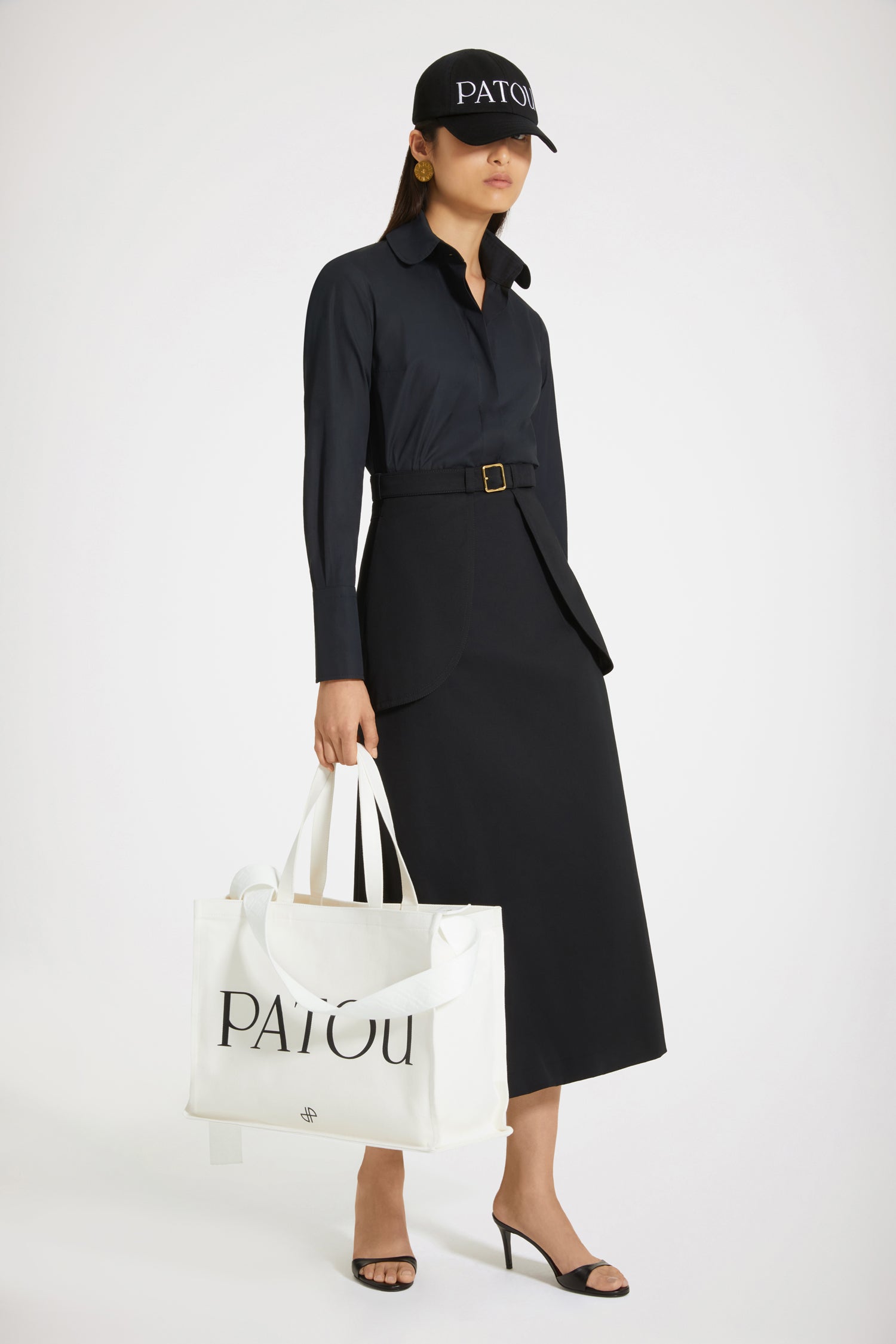 Patou - Gonna midi con maxi tasche in cotone bio - Black - Le maxi tasche, un dettaglio très Patou.Gonna in gabardine di cotone bio nero. Lunghezza midi. Silhouette svasata. Cintura regolabile in vita con fibbia oro. Maxi tasche sul davanti. Cucitura a V e pinces sul retro. Cuciture ton-sur-ton.Spring-Summer 2023 Show - Look #06