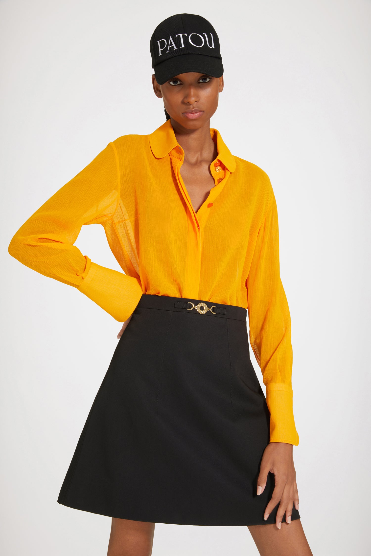 Patou - Jupe courte à médaillon en coton bio - Black - La petite jupe évasée se pare d'une touche Patou dorée. Jupe en gabardine de coton bio noir. Modèle court et évasé. Médaillon doré gravé Patou à la taille. Pinces à l'avant et au dos. Zip au dos.Le médaillon peut être enlevé.