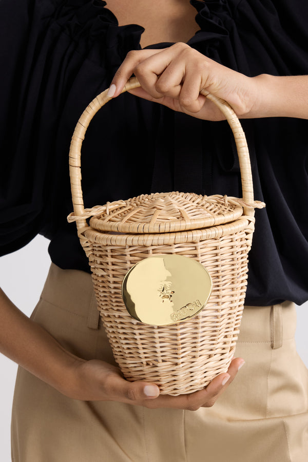 Patou - Korbtasche - Vanilla - Vanillefarbene Korb-Handtasche. Henkel mit Schiebedeckel. Goldfarbene, von der „Bocca della Verità“ inspirierte Verzierung.Diese Tasche wurde in Handarbeit gefertigt. Sie kann daher geringfügige Unregelmäßigkeiten aufweisen.