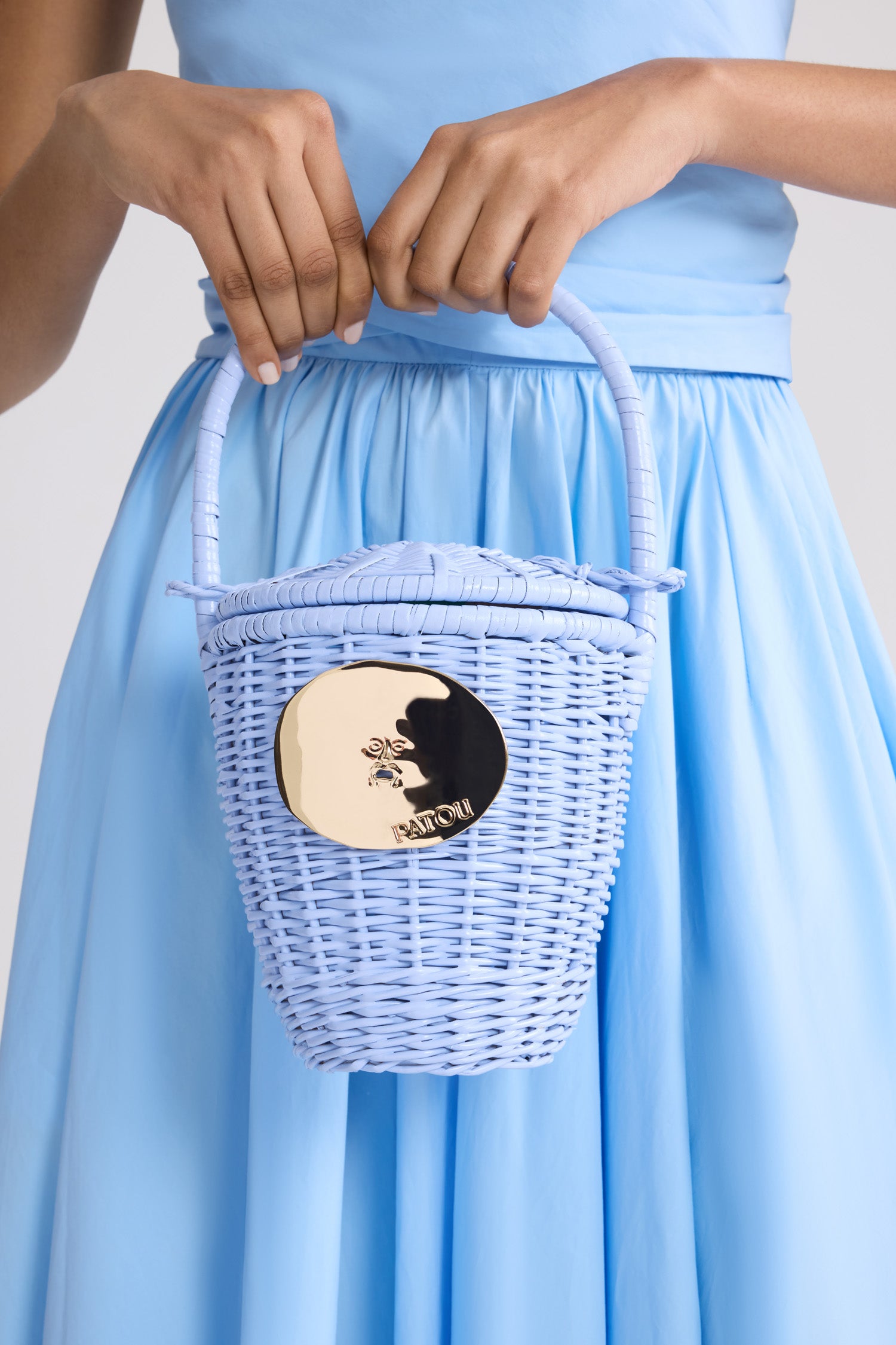 Patou - Sac Seau Iconique en Osier - Riviera Blue - Sac seau bleu clair. Matière en osier. Médaillon doré gravé Patou.