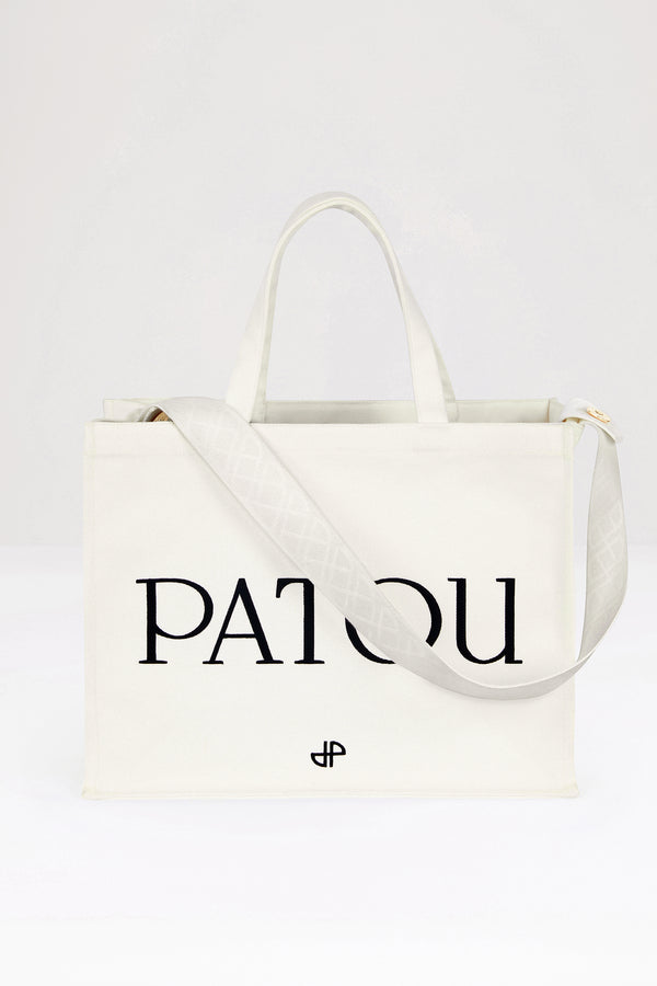 Patou - 오가닉 코튼 파투 캔버스 토트백 - Cream - 크림 컬러의 오가닉 코튼 소재. Patou 레터링 로고, 블랙 컬러의 JP 모노그램 장식. 한쪽 측면에 골드 버튼, 반대편에 사이즈 조절이 가능한 매듭 리본이 있는 엠보싱 처리된 화이트 숄더 스트랩. 두 개의 탑 핸들. 토트백 또는 숄더백으로 착용 가능.
