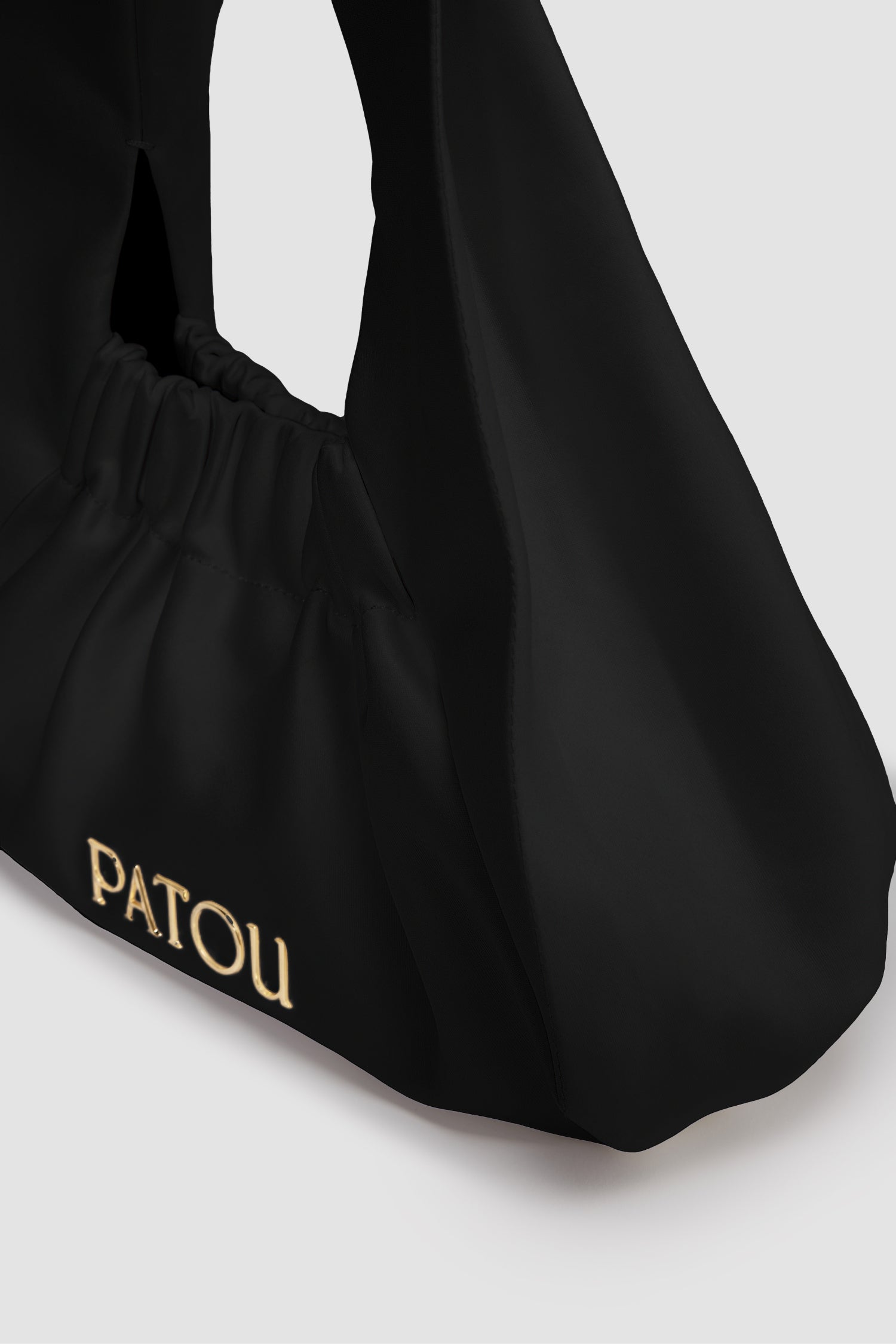 Patou - Die Le Biscuit Tasche - Black - Tasche aus Baumwollmisch-Satin in Schwarz. Kleines Modell. Hobo-Form mit integriertem, breiten Riemen. Öffnung mit Gummizug. Patou-Logo aus goldfarbenem Metall. Baumwollfutter.