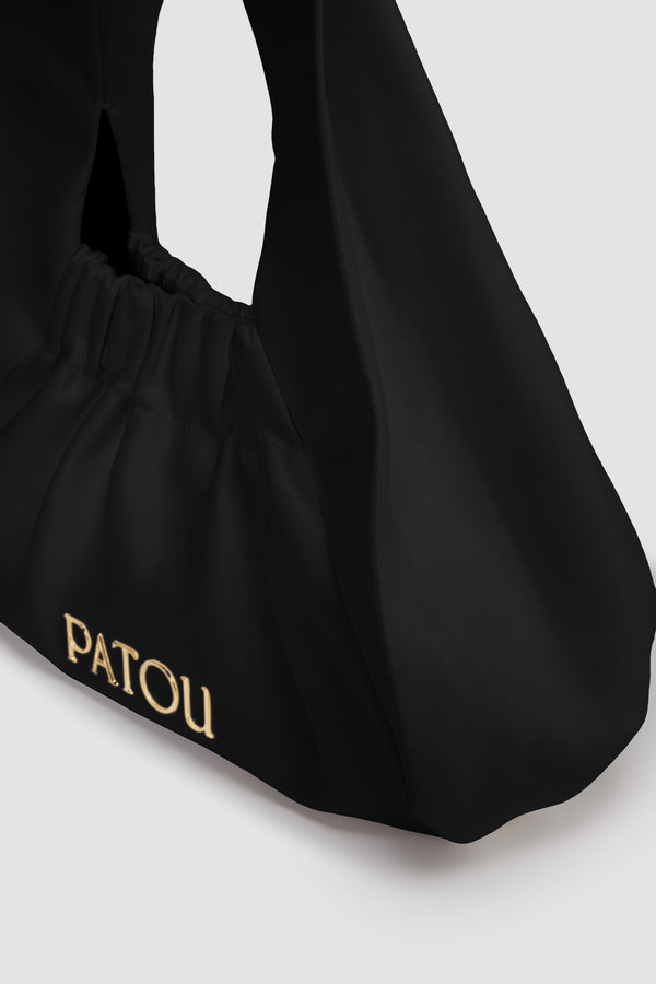 Patou - 비스킷 백 - Black - 블랙 코튼 혼방 새틴 소재. 스몰 버전. 넓은 스트랩이 내장된 호보 쉐입. 신축성 있는 오프닝. 골드 톤 메탈 Patou 로고. 코튼 안감.