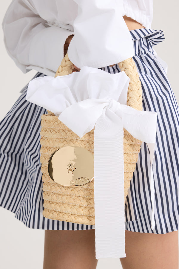 Patou - ラフィア アイコニック バケットバッグ - White - 天然ラフィア製バケットバッグ。編み込みのトップハンドル。パトゥ ロゴのエングレービング入り、「真実の口」から着想を得たゴールドカラーの装飾。ホワイトのファブリックライニング、ファイユフリル付き、グログランドローストリング付き。