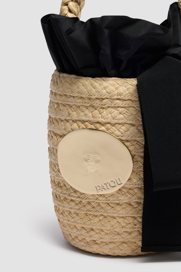 Patou - ラフィア アイコニック バケットバッグ - Vanilla - バニラのラフィア製バケットバッグ。編み込みのトップハンドル。「真実の口」から着想を得たゴールドトーンのディテール、パトゥ ロゴのエングレービング入り。ラッフルおよびボウ付き、ファブリック裏地付き