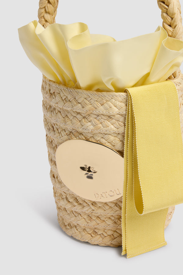 Patou - Sac Seau GG en Raphia - Citrus Blossom - Sac seau naturel. Matière en raphia. Médaillon doré gravé Patou. Ruban jaune.