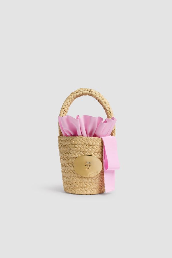 Patou - Sac Seau GG en Raphia - Primrose Pink - Sac seau naturel. Matière en raphia. Médaillon doré gravé Patou. Ruban rose.