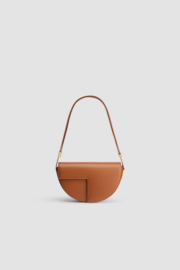 Patou - Le Patou bag in leather - Autumn Leaf - Autumn Leaf brown leather handbag. Crafted using unique materials sourced from unused high-quality leather hides. 60 limited numbered edition. Half-circle shape with geometric cut-outs inspired by the JP monogram. Gold-tone hardware with JP monogram detail at the side. Adjustable strap that allows it to be worn on the shoulder, across the body or carried by hand. Magnetic closure with gold-tone JP detail. Multiple compartments inside. Eco lining.Measures: 25 cm (length), 15 cm (height), 6 cm (depth)3 lengths for the adjustable strap: 47 cm (on the shoulder), 36 cm (across the body), 28 cm (carried by hand)