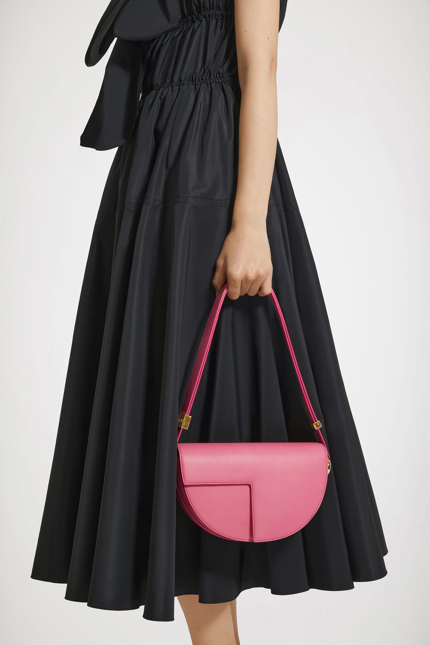 Patou - Le Patou - Pink - Le Patou a plus d&amp;#39;un tour dans son sac !Sac en cuir rose. Édition limitée et numérotée disponible en 60 exemplaires. Forme demi-lune avec découpes géométriques inspirée du monogramme JP. Pièces en métal doré avec détail JP inspiré d&amp;#39;une broche des archives Jean Patou. Bandoulière ajustable permettant un porté épaule, en bandoulière ou à la main. Fermeture aimantée avec détail JP doré. Compartiments multiples à l&amp;#39;intérieur.Dimensions : 25 cm de longueur, 15 cm de hauteur et 6 cm de profondeur.Bandoulière ajustable en 3 longueurs : 47 cm (sur l&amp;#39;épaule), 36 cm (en bandoulière), 28 cm (porté à la main)