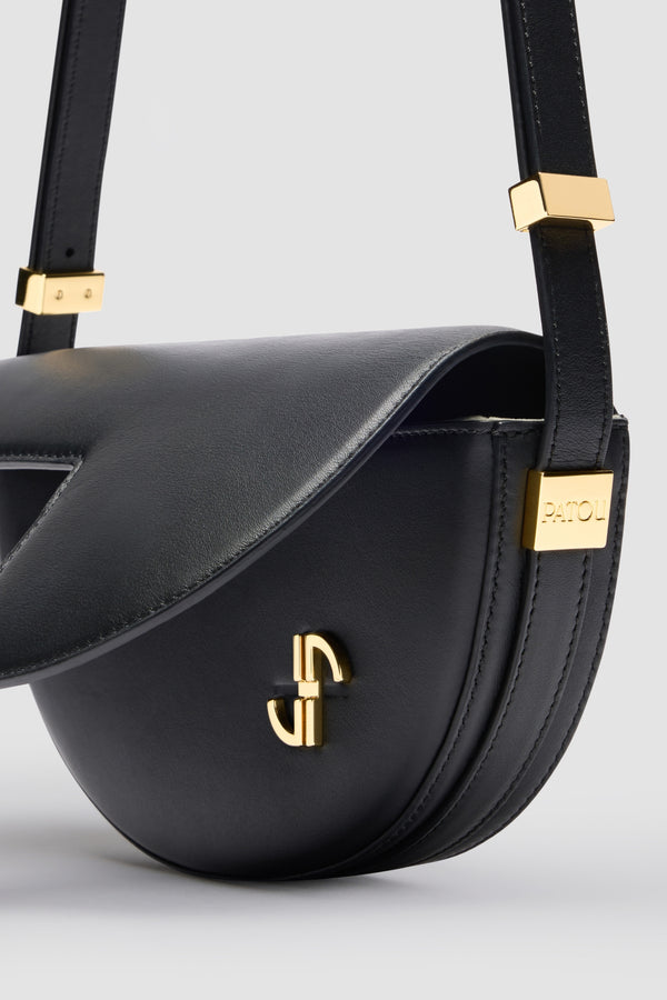 Patou - 르 쁘띠 파투 백 - Black - 작은 사이즈로 제작된 파투의 시그니처 파투 백.  블랙 컬러의 가죽 소재. 미사용 상태의 고품질 가죽 하이드로 만든 특수 소재로 제작된 백. 200점 한정 생산 리미티드 에디션. JP 모노그램에서 영감을 받은 기하학적 컷아웃이 돋보이는 반원형 실루엣. 측면의 Patou가 새겨진 골드 톤 하드웨어. 길이 조절 가능한 스트랩으로 숄더백, 크로스백, 또는 토트백 스타일로 연출 가능. 골드 톤 JP 디테일의 자석 잠금장치. 내부 수납공간. 에코 내부 마감.사이즈: 20cm(길이), 13cm(높이), 5cm(깊이)