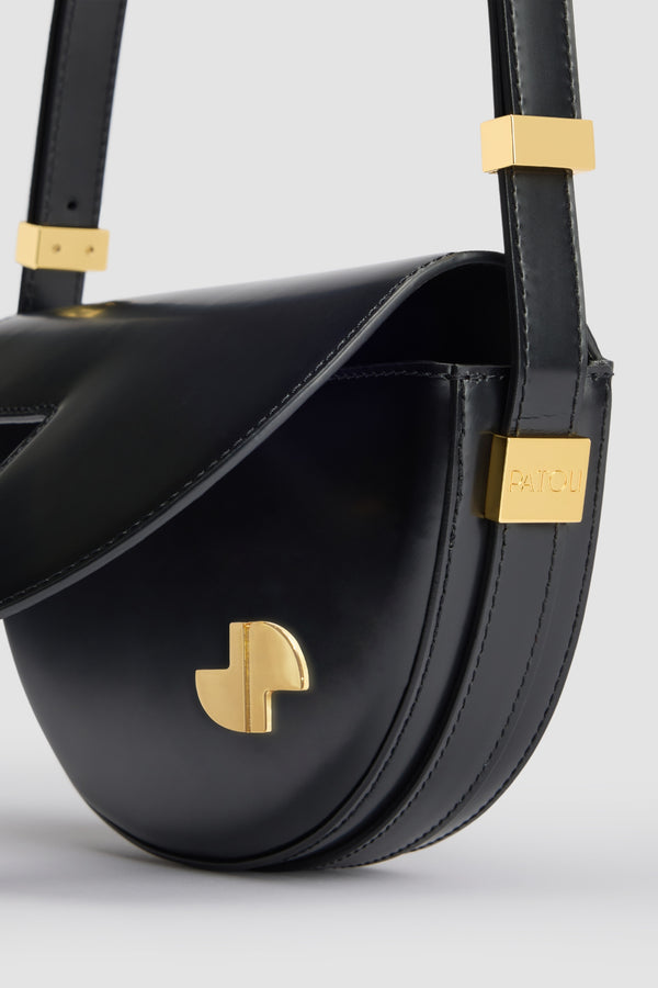 Patou - Le Petit Patou bag in leather - Black - Black leather handbag. Half-circle shape with geometric cut-outs inspired by the JP monogram. Gold-tone hardware with Patou-engraved detail at the side. Adjustable strap that allows it to be worn on the shoulder, across the body or carried by hand. Magnetic closure with gold-tone JP detail. Internal compartment. Eco lining.Measures: 20cm (length), 13cm (height), 5cm (depth)