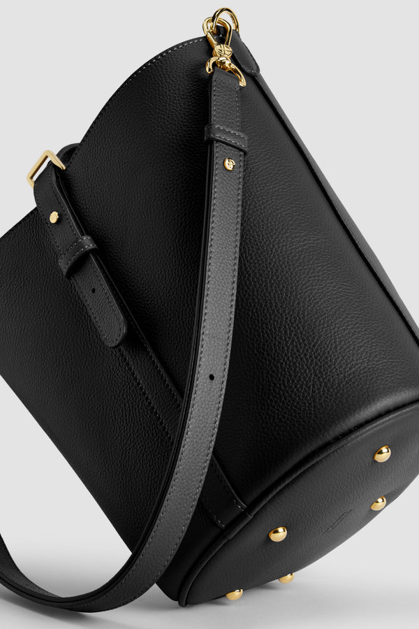 Patou - Sac seau JP en cuir - Black - Sac en cuir grainé noir. Forme seau avec JP 3D sur le devant. Fermeture par patte boutonnée. Bandoulière détachable et réglable. Pièces métalliques dorées. Pieds en métal.