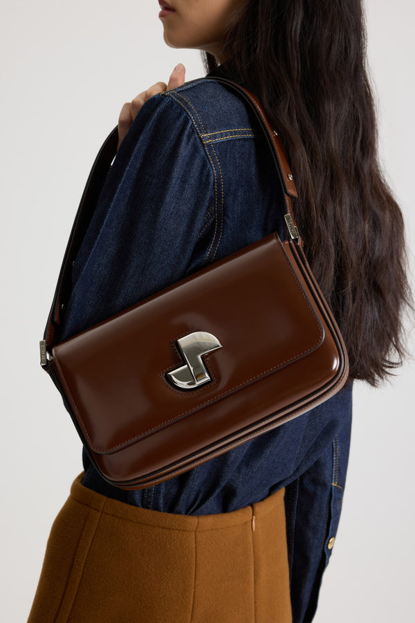 Patou - Le Classic Lock Tasche aus Leder - Smoked Ebony - Tasche aus glänzendem Leder in Rauchig-Ebenholz. Klassische Tagestasche mit einem gewissen Etwas. Goldener Art déco-JP-Drehverschluss an der Vorderseite. Durch den verstellbaren Riemen kann sie kurz oder lang getragen werden. Innenfutter aus Leder.
