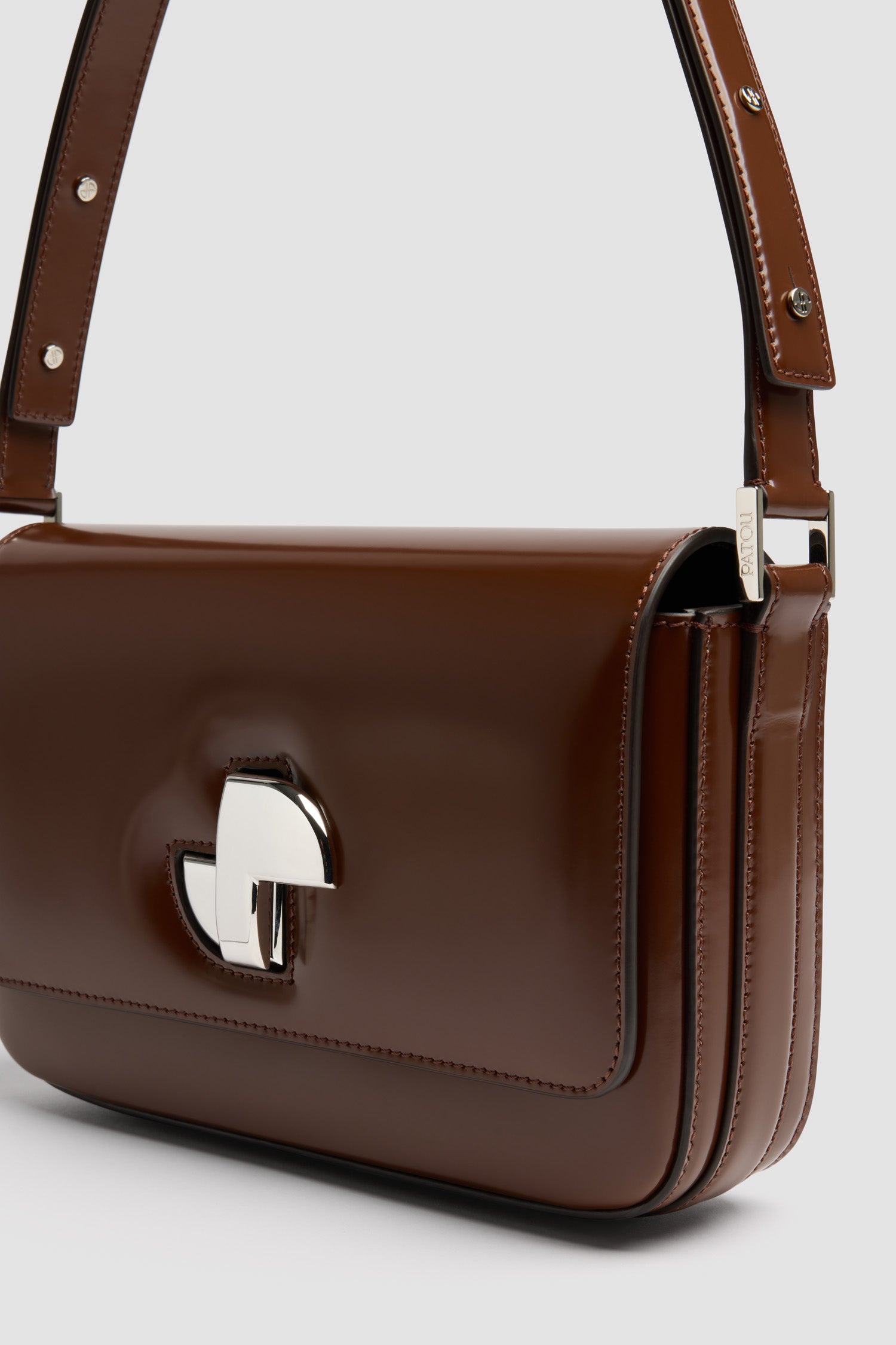 Patou - Sac Le Classic Lock en cuir - Smoked Ebony - Sac à main en cuir brillant couleur ébène fumé. Sac de jour classique revisité. Fermoir rotatif JP doré d’inspiration Art Déco sur le devant. Bandoulière réglable pouvant être portée courte ou longue. Doublure en cuir.