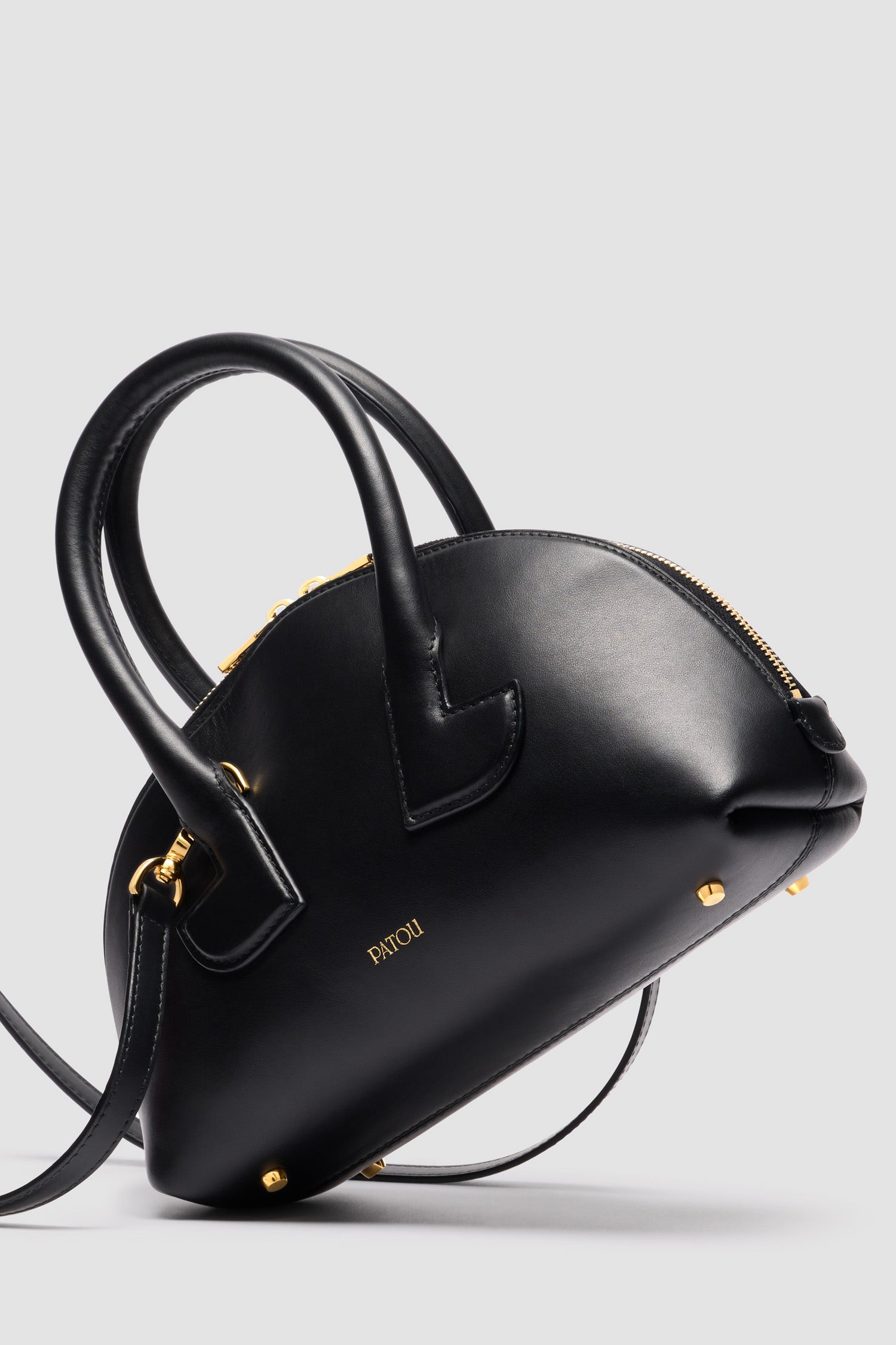 Patou - Le Patou Bowling bag in leather - Black - Black smooth leather handbag. Bowling shape. Two top handles with geometric cut-out details. Removable shoulder strap. Two-way gold-tone top zip fastening. Gold-embossed Patou logo at the front. Gold-tone metal feet.