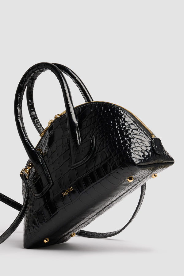 Patou - Borsa Le Patou Bowling in pelle di coccodrillo goffrata - Black - Borsa in pelle di coccodrillo goffrata nera. Forma bowling. Doppio manico con dettagli geometrici. Tracolla rimovibile. Chiusura con zip oro a doppio cursore. Logo Patou oro goffrato sul davanti. Piedini in metallo oro.