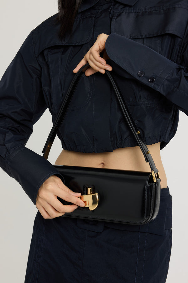 Patou - Le Lock en cuir - Black - Sac en cuir brillant noir. Sac de jour classique revisité. Forme allongée. Fermoir rotatif JP doré d'inspiration Art Déco sur le devant. Bandoulière réglable pouvant être portée courte ou longue. Doublure en cuir.