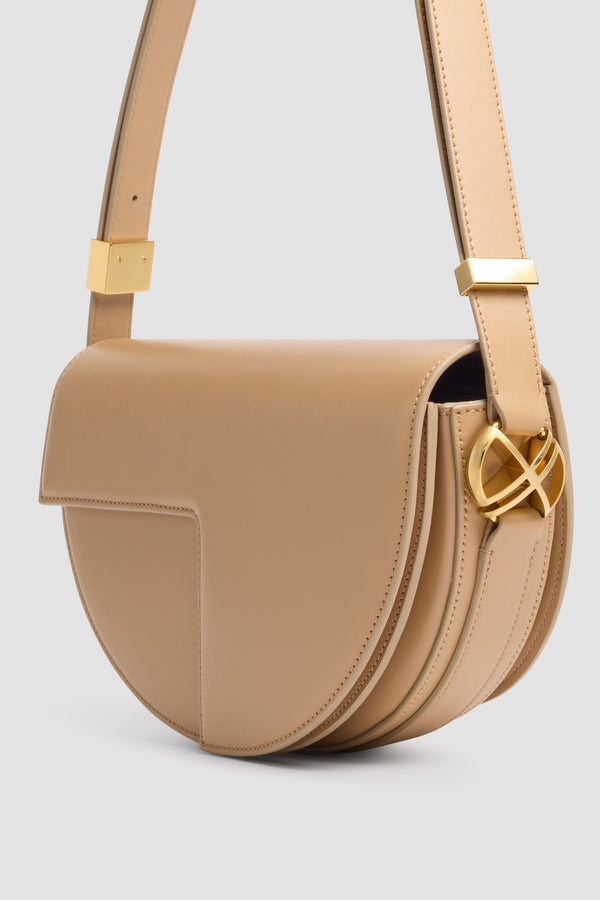 Patou - Le Patou Ledertasche - Sand - Le Patou Tasche aus sandfarbenem Leder. Halbmondform. Verstellbarer und abnehmbarer Schultergurt. Überschlag mit goldenem JP-Monogramm.
