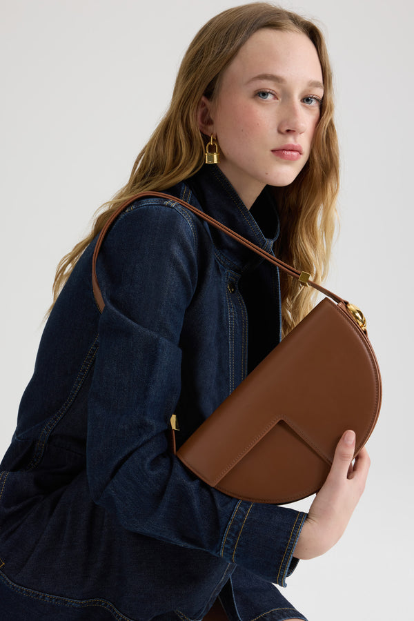 Patou - Borsa Le Patou in pelle - Mahogany - Borsa in pelle liscia mogano. Forma a mezzaluna con tagli geometrici ispirati al monogramma JP. Pezzi in metallo oro con monogramma JP sul lato. Tracolla regolabile che consente di portare la borsa a spalla, a bandoliera o a mano. Chiusura magnetica con dettaglio JP oro. Compartimenti interni multipli.Dimensioni: 25 cm (lunghezza), 15 cm (altezza), 6 cm (larghezza)Tracolla regolabile con tre lunghezze: 47 cm (sulla spalla), 36 cm (crossbody), 28 cm (a mano)