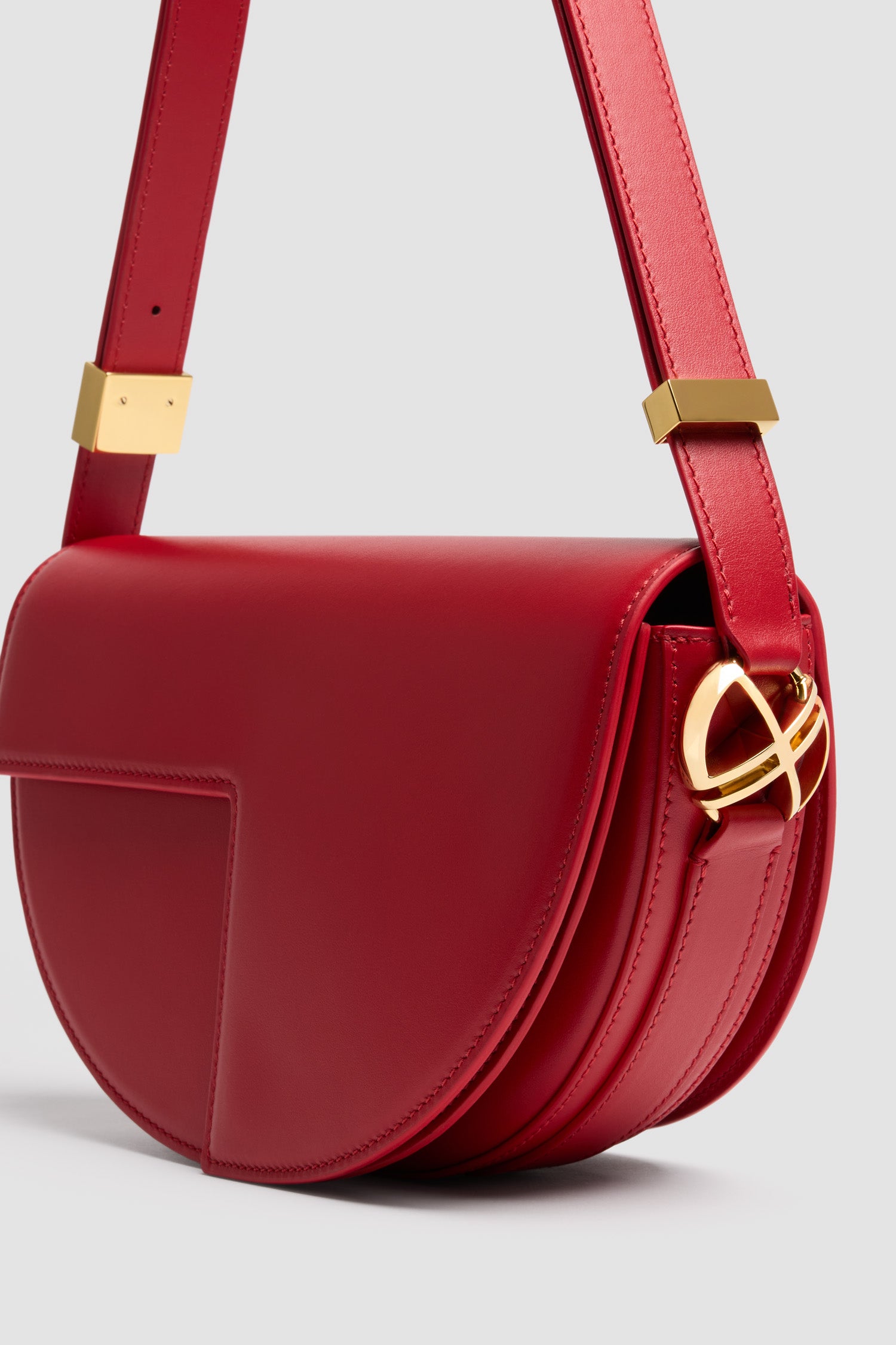 Patou - Le Patou bag in leather - Elixir Red - Elixir Red smooth leather handbag. Half-circle shape with geometric cut-outs inspired by the JP monogram. Gold-tone hardware with JP monogram detail at the side. Adjustable strap that allows it to be worn on the shoulder, across the body or carried by hand. Magnetic closure with gold-tone JP detail. Multiple compartments inside.Measures: 25 cm (length), 15 cm (height), 6 cm (depth)3 lengths for the adjustable strap: 47 cm (on the shoulder), 36 cm (across the body), 28 cm (carried by hand)