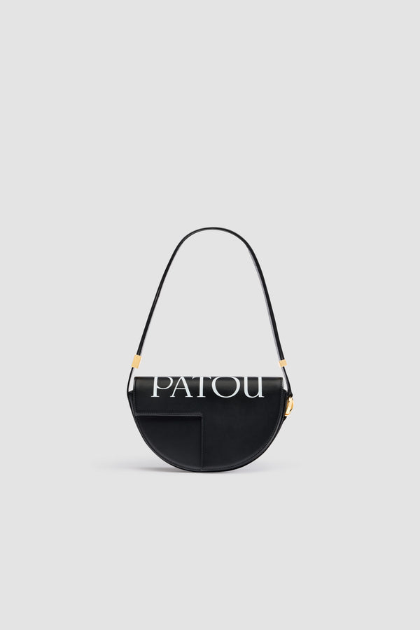 Patou - Le Patou - Black and White - Sac en cuir lisse noir. Logo Patou imprimé sur le dessus. Forme demi-lune avec découpes géométriques inspirée du monogramme JP. Pièces en métal doré avec détail JP inspiré d&#39;une broche des archives Jean Patou. Bandoulière ajustable permettant un porté épaule, en bandoulière ou à la main. Fermeture aimantée avec détail JP doré. Compartiments multiples à l&#39;intérieur.Dimensions : 25 cm de longueur, 15 cm de hauteur et 6 cm de profondeurBandoulière ajustable en 3 longueurs : 47 cm (sur l&#39;épaule), 36 cm (en bandoulière), 28 cm (porté à la main)