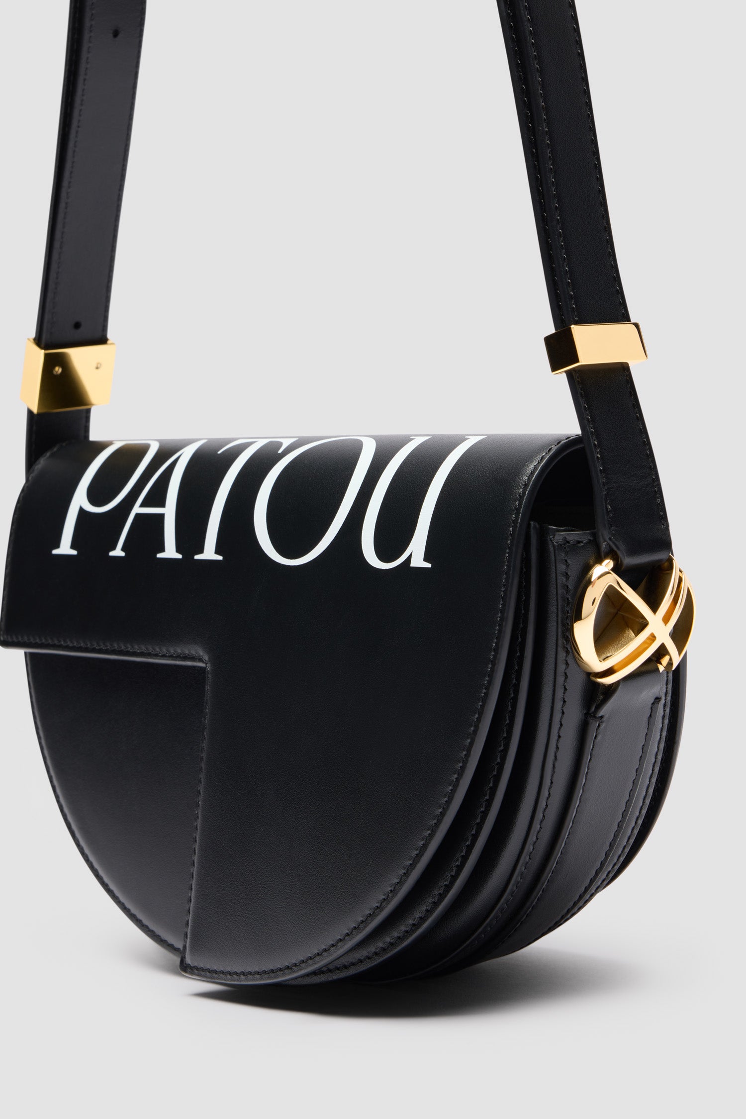 Patou - Le Patou Tasche aus Leder - Black and White - Schwarze Handtasche aus Glattleder. Weißes Patou Logo als Print auf der Oberseite. Halbkreis-Format mit geometrischen, vom JP-Monogramm inspirierten Cut-Outs. Goldfarbene Metallelemente mit JP-Monogramm-Detail an der Seite. Verstellbarer Riemen zum Tragen über der Schulter, diagonal am Körper oder in der Hand. Magnetverschluss mit goldfarbenem JP-Detail. Mehrere Fächer auf der Innenseite.Maße: 25 cm (Länge), 15 cm (Höhe), 6 cm (Tiefe)3 Längen für den verstellbaren Riemen: 47 cm (zum Tragen über der Schulter), 36 cm (zum Tragen diagonal am Körper), 28 cm (zum Tragen in der Hand)