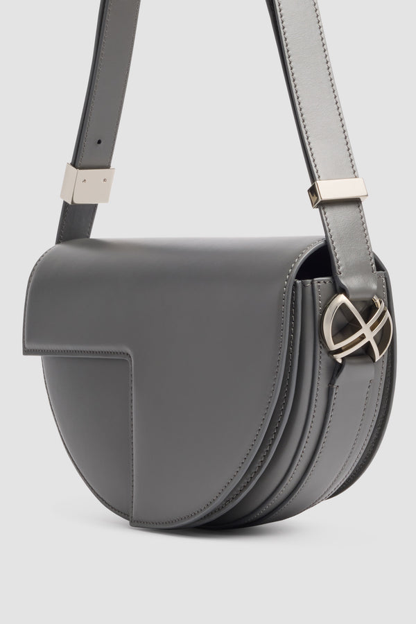 Patou - Le Patou Leather Bag - Stormy Sea - Le Patou bag in grey leather. Half-moon shape. Adjustable and removable shoulder strap. Flap closure with silver JP monogram.
