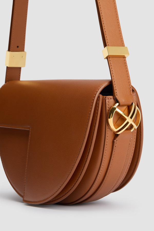 Patou - Borsa Le Patou in pelle - Caramel - Borsa in pelle lucida color caramello. Realizzata con pellami recuperati dal ciclo di produzione. Forma a mezzaluna con tagli geometrici ispirati al monogramma JP. Pezzi in metallo oro con dettaglio JP ispirato a una spilla dell&#39;archivio Jean Patou. Tracolla regolabile che permette di indossarla in più modi: in spalla, crossbody o a mano. Chiusura magnetica con dettaglio JP oro. Compartimenti interni multipli. Fodera in ecocamoscio.Dimensioni : lunghezza: 25 cm; altezza: 15 cm; larghezza: 6 cmTracolla regolabile con tre lunghezze: 47 cm (sulla spalla), 36 cm (crossbody), 28 cm (a mano).