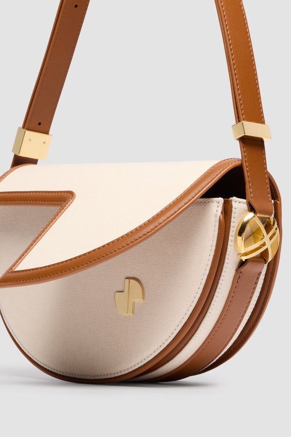 Patou - Le Patou bag in leather and canvas - Caramel - Caramel leather and natural cotton canvas handbag. Half-circle shape with geometric cut-outs inspired by the JP monogram. Gold-tone hardware with JP monogram detail at the side. Adjustable strap that allows it to be worn on the shoulder, across the body or carried by hand. Magnetic closure with gold-tone JP detail. Multiple compartments inside.Measures: 25 cm (length), 15 cm (height), 6 cm (depth)3 lengths for the adjustable strap: 47 cm (on the shoulder), 36 cm (across the body), 28 cm (carried by hand)