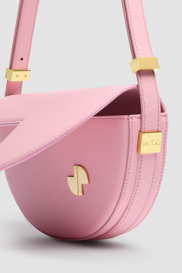Patou - Le Petit Patou bag in leather - Primrose Pink - Primrose Pink smooth leather handbag. Half-circle shape with geometric cut-outs inspired by the JP monogram. Gold-tone hardware with Patou logo-engraved detail at the side. Adjustable strap that allows it to be worn on the shoulder, across the body or carried by hand. Magnetic closure with gold-tone JP detail. Internal compartment.Measures: 20 cm (length), 13 cm (height), 5 cm (depth)