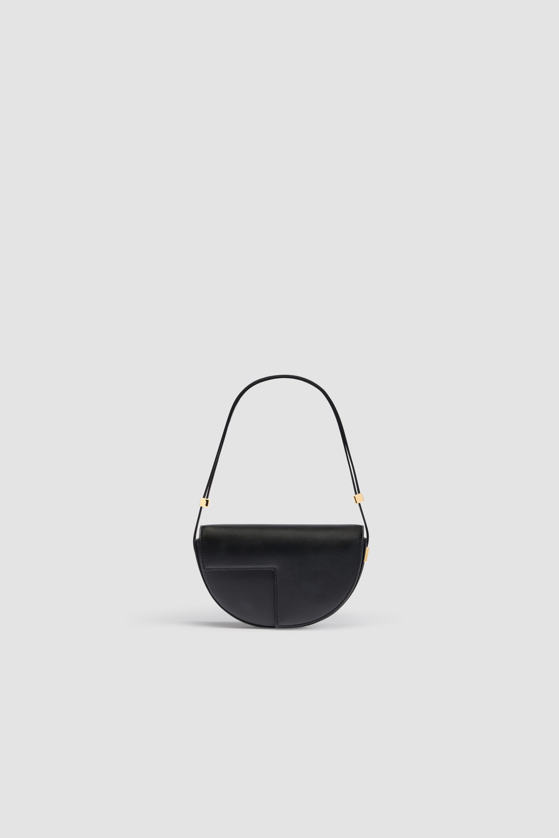 Patou - Le Petit Patou bag in leather - Black - Black leather handbag. Half-circle shape with geometric cut-outs inspired by the JP monogram. Gold-tone hardware with Patou-engraved detail at the side. Adjustable strap that allows it to be worn on the shoulder, across the body or carried by hand. Magnetic closure with gold-tone JP detail. Internal compartment. Eco lining.Measures: 20cm (length), 13cm (height),  5cm (depth)