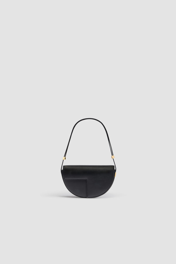 Patou - Le Petit Patou bag in leather - Black - Black leather handbag. Half-circle shape with geometric cut-outs inspired by the JP monogram. Gold-tone hardware with Patou-engraved detail at the side. Adjustable strap that allows it to be worn on the shoulder, across the body or carried by hand. Magnetic closure with gold-tone JP detail. Internal compartment. Eco lining.Measures: 20cm (length), 13cm (height),  5cm (depth)