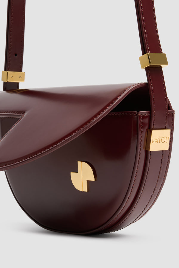 Patou - Borsa Le Petit Patou in pelle - Syrah - Borsa in pelle lucida borgogna Syrah. Forma a mezzaluna con tagli geometrici ispirati al monogramma JP. Pezzi in metallo oro con logo Patou inciso sul lato. Tracolla regolabile che consente di portare la borsa a spalla, a bandoliera o a mano. Chiusura magnetica con dettaglio JP oro. Compartimento interno.Dimensioni: 20 cm (lunghezza), 13 cm (altezza), 5 cm (larghezza)
