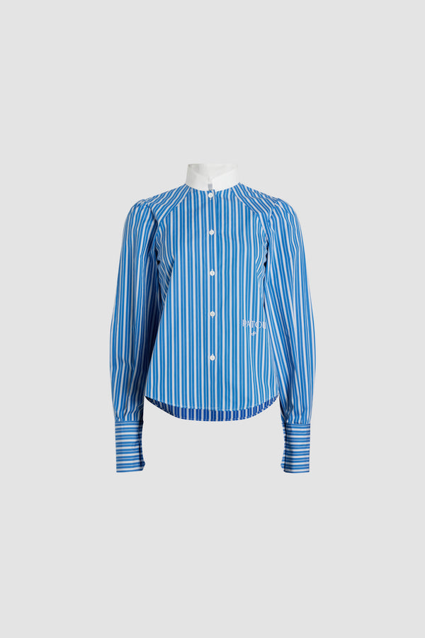 Patou - Lavallière blouse in printed sustainable cotton - Victoria Blue Stripes - Victoria Blue sustainable cotton blouse. Striped pattern. Contrast stand collar with removable lavallière bow. JP-engraved mother-of-pearl buttons. Volume raglan sleeves with puff shoulders and buttoned French cuffs. Embroidered Patou and JP at the front.