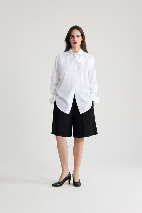 Patou - Chemise safari en coton bio - White - Chemise en coton bio blanc. Coupe droite. Col de chemise. Gorge cachée avec boutons en nacre gravés JP. Poches hautes à la poitrine. Poignets boutonnés.