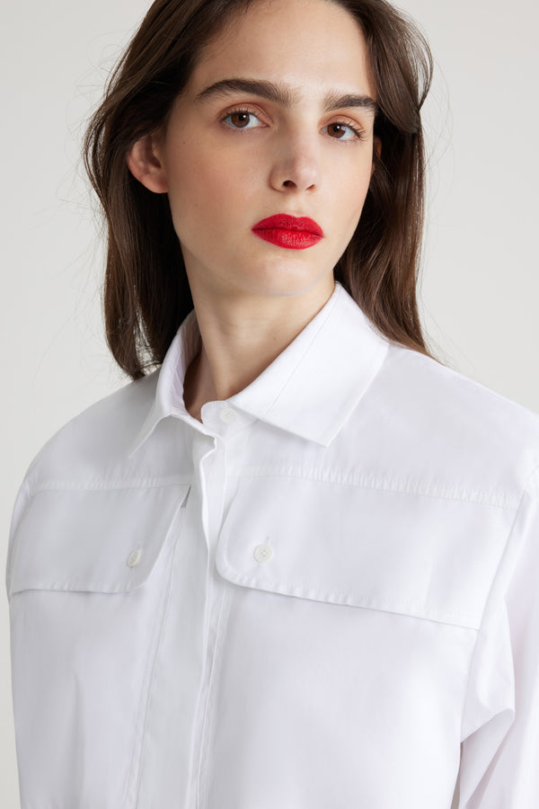 Patou - Chemise safari en coton bio - White - Chemise en coton bio blanc. Coupe droite. Col de chemise. Gorge cachée avec boutons en nacre gravés JP. Poches hautes à la poitrine. Poignets boutonnés.