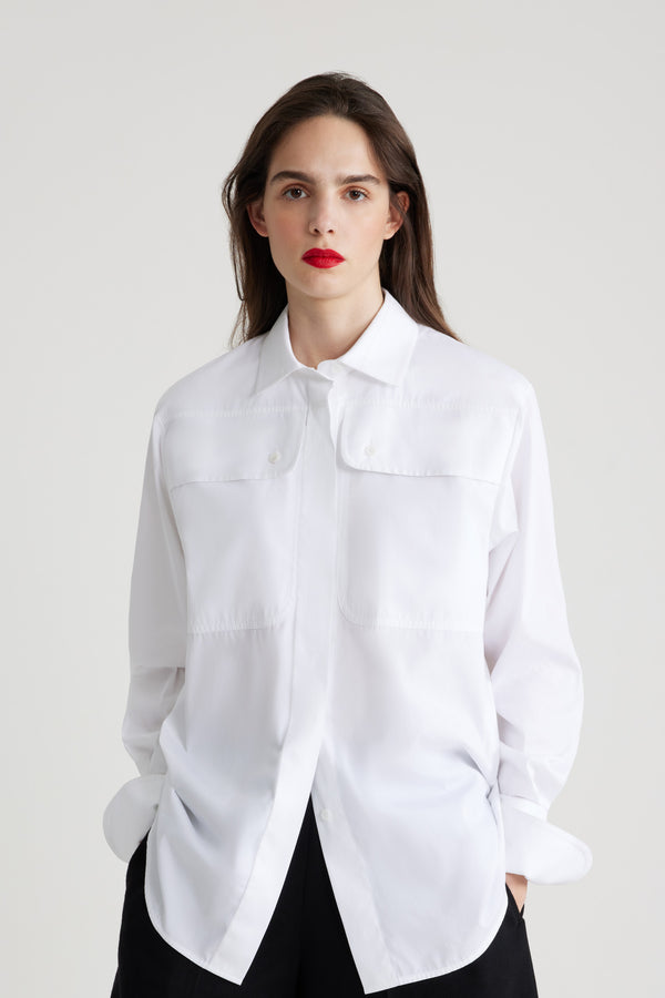 Patou - Chemise safari en coton bio - White - Chemise en coton bio blanc. Coupe droite. Col de chemise. Gorge cachée avec boutons en nacre gravés JP. Poches hautes à la poitrine. Poignets boutonnés.