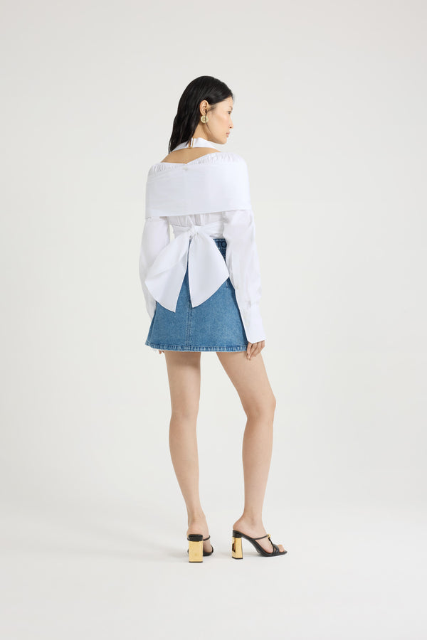 Patou - オーガニック コットンポプリン ラップブラウス - White - ホワイトのオーガニックコットンポプリン製ブラウス。バスト周りに巻きつけて背面で結ぶ、取り外し可能なトップレイヤーデザイン。伸縮性のあるショルダーとグログランホルターネックストラップを配したワイドなネックライン。隠しボタン留め。袖口にボタン付きの長めのスリーブ。前面にJPモノグラム刺繍。
